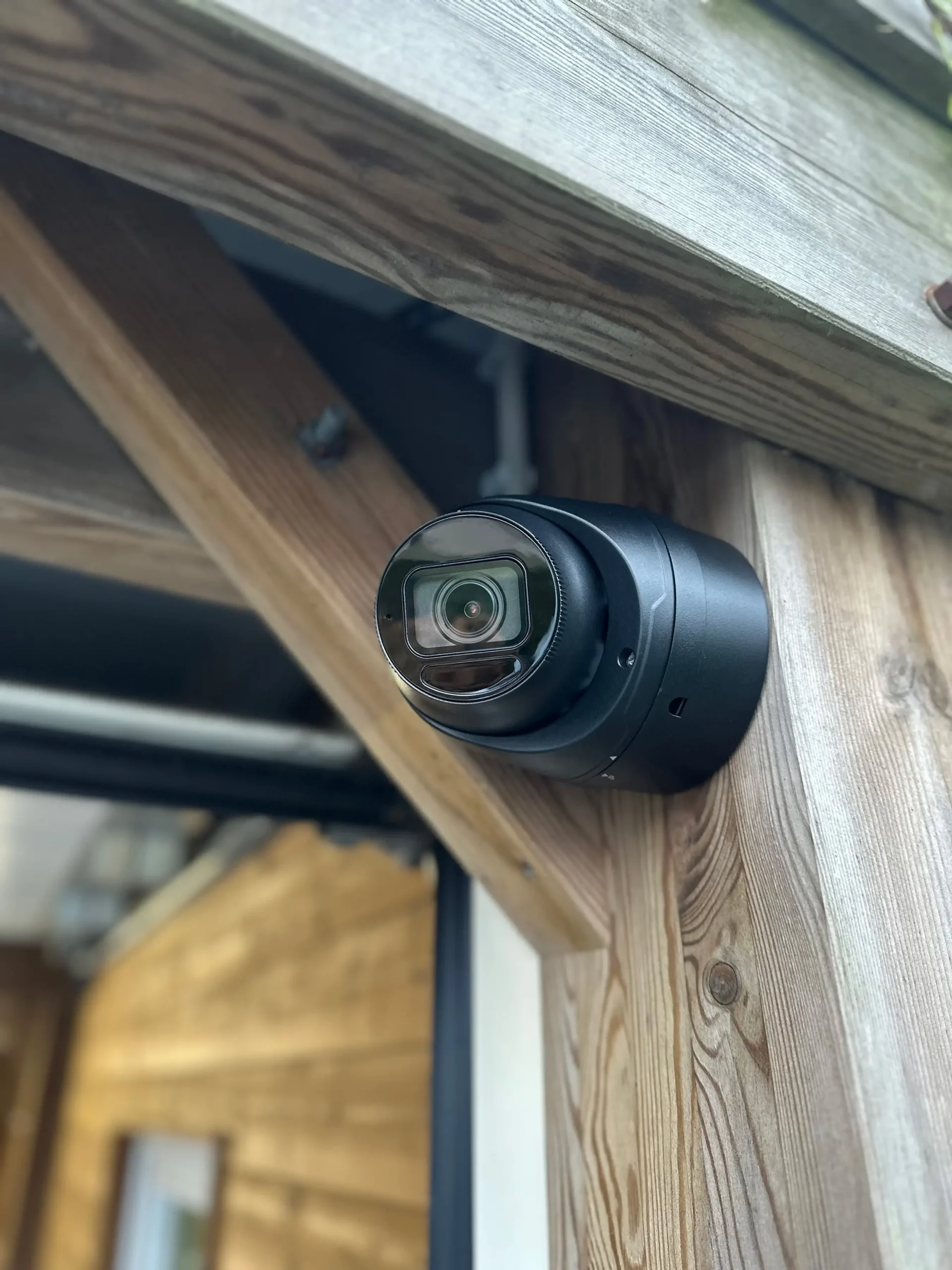 Een gemonteerde beveiligingscamera op een houtenpaal van een carport buiten